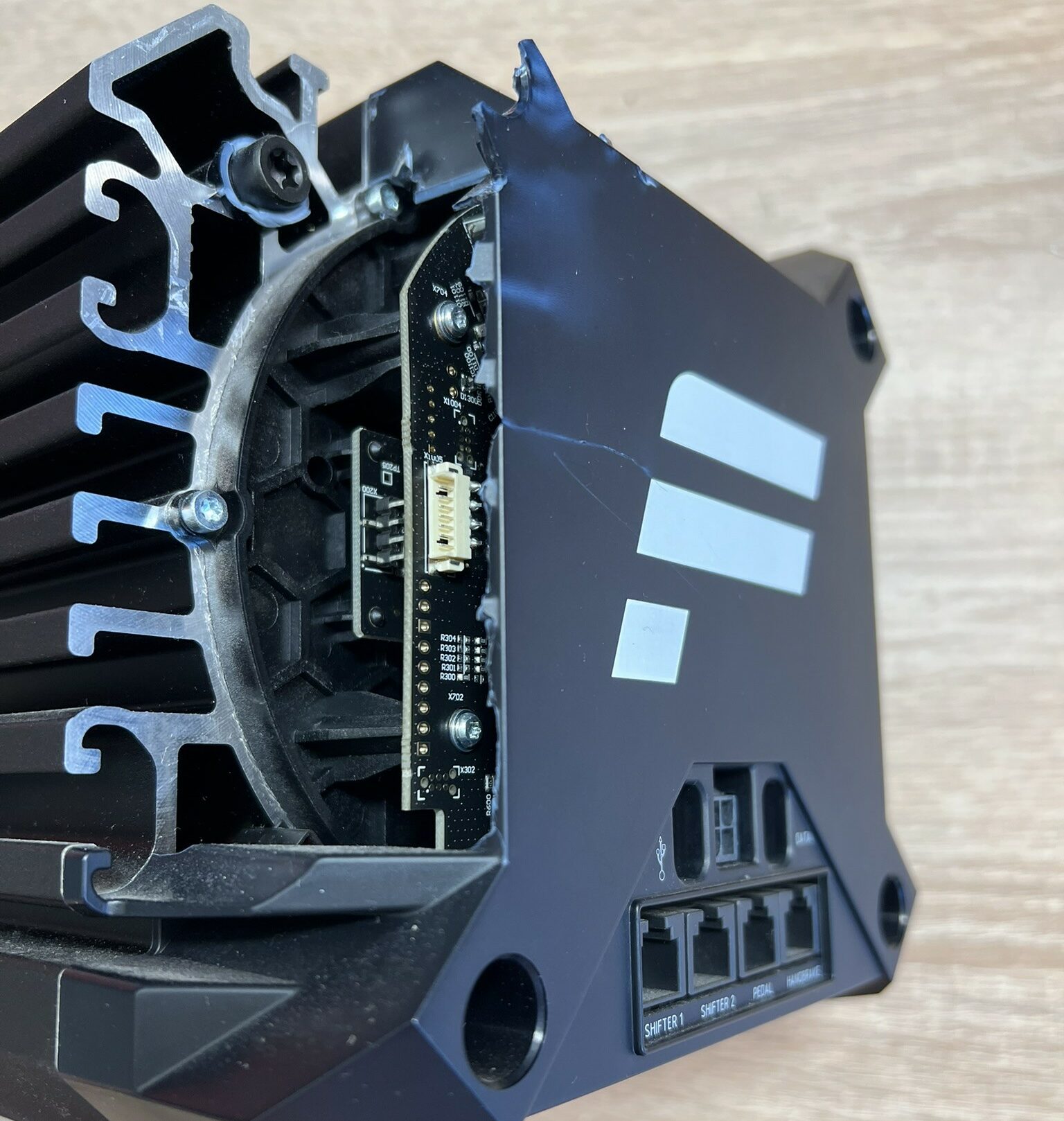 Baza simracingowa Fanatec CSL DD po upadku, widoczne spękania obudowy, elektronika (PCB) wystająca ze środka